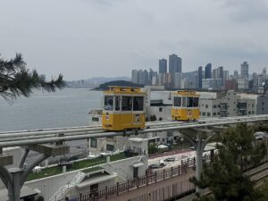 海雲台の海を背景に高架レールを走る黄色いスカイカプセル