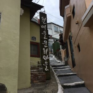 ヒンヨウル文化村の看板と住宅の間を上る細い階段