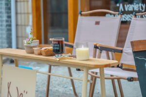 飲み物と軽食、キャンドルが置かれた木製テーブルと布張りの椅子